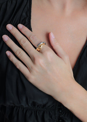 A person in a black top rests their hand on their chest, displaying the Anabel Aram Farrier Mixed Metal Triple Band Ring with a subtle hammered texture on their middle finger.