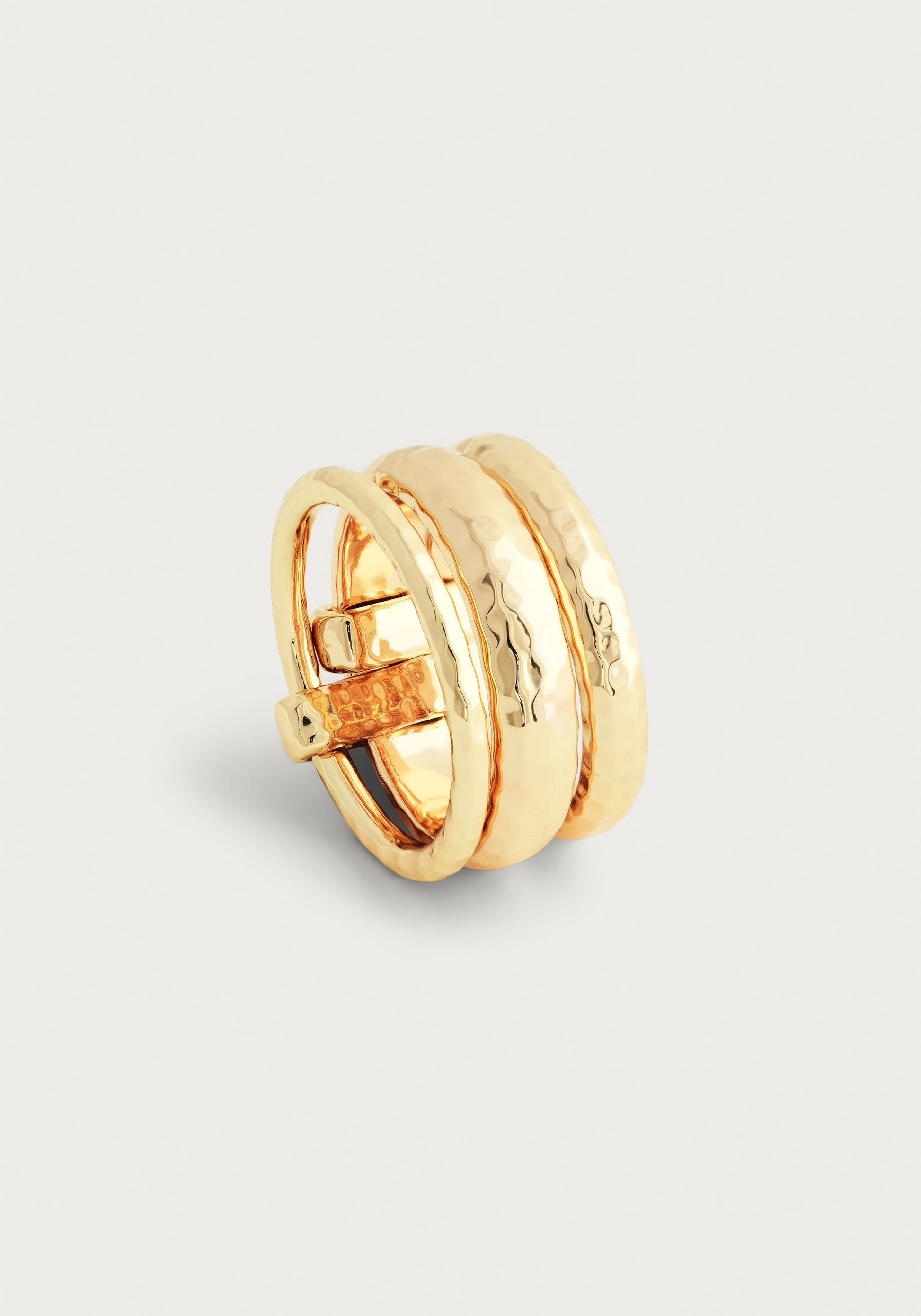 The Anabel Aram Farrier Triple Connected Ring features a gold-tone wide band with a hammered texture and overlapping, belted design, shown against a plain light background, highlighting its unique style.