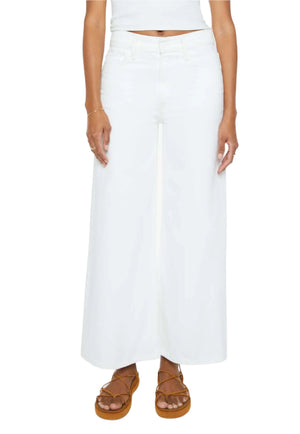 A person wearing Mother’s The Ditcher Roller Zip Ankle high-waisted white jeans, a matching top, and brown strappy sandals is shown from shoulders to feet against a white background.