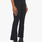 A person wearing Mother’s The Hustler Ankle Fray high-waist flare jeans in stretch denim, paired with a white top and black heeled ankle boots, stands against a plain white background.