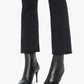 Person wearing black pointed-toe heeled ankle boots and Mother’s The Hustler Ankle Fray high-waist flare jeans with a raw hem against a white background.