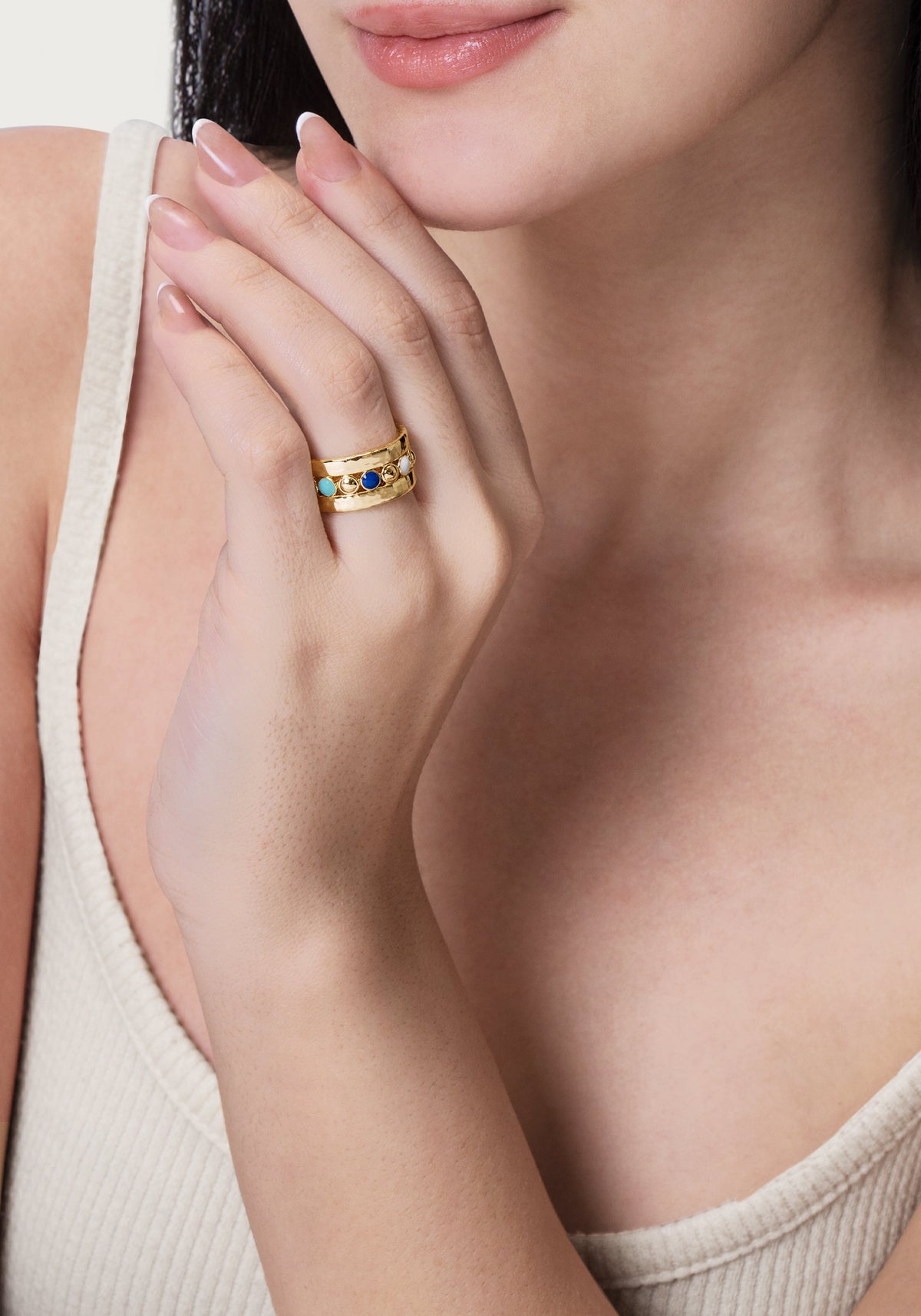 Anabel Aram Milos Multicolor Ring featuring a wide 18K gold plated band with a row of inlaid round turquoise, blue, and white stones worn on a hand.