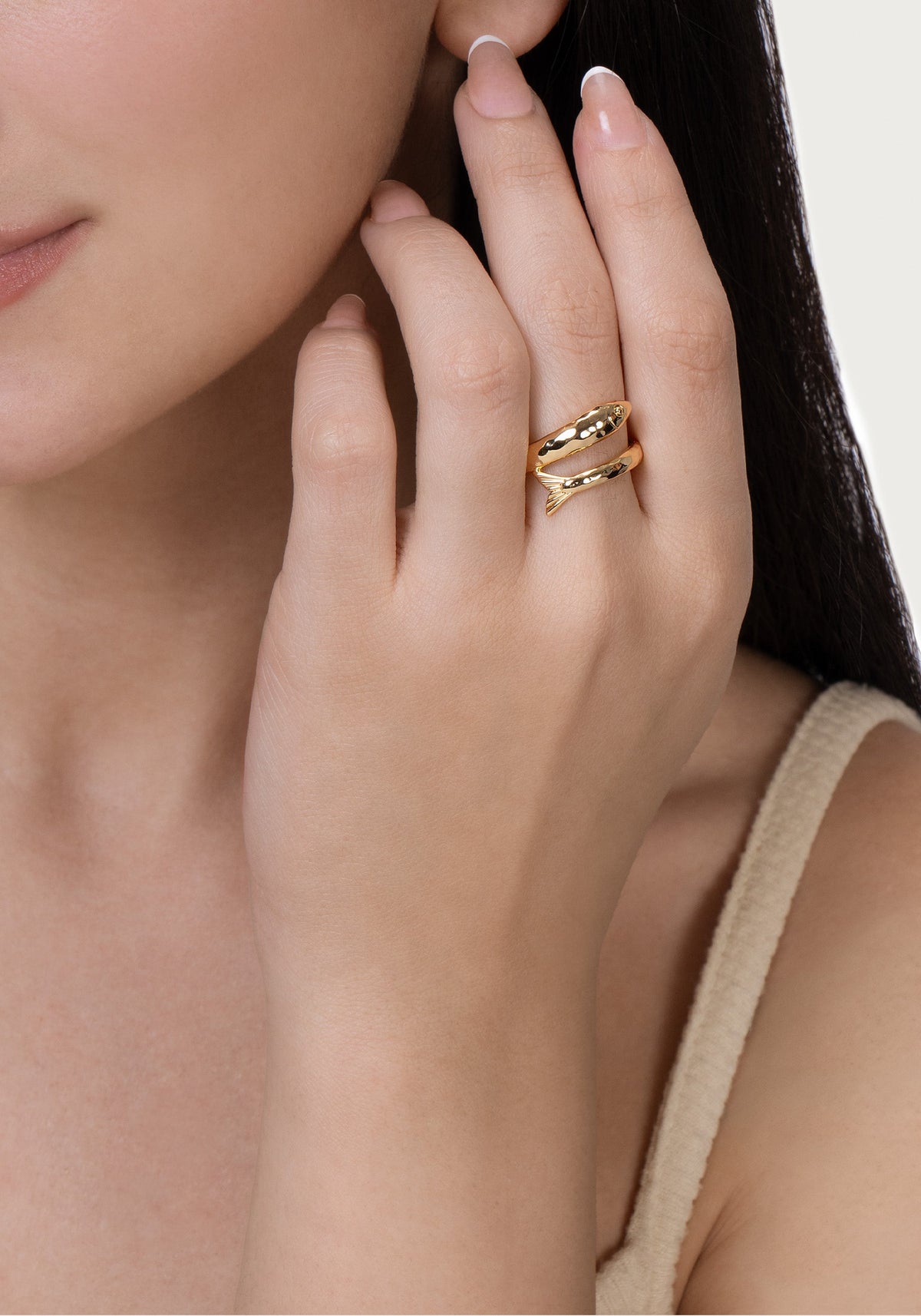 An 18K gold plated Milos Fish Ring shaped like a stylized fish wrapped around a finger.