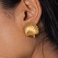 Close-up of a person's ear wearing Mar Earrings by Jennifer Behr, crafted in the shape of a golden scallop shell.