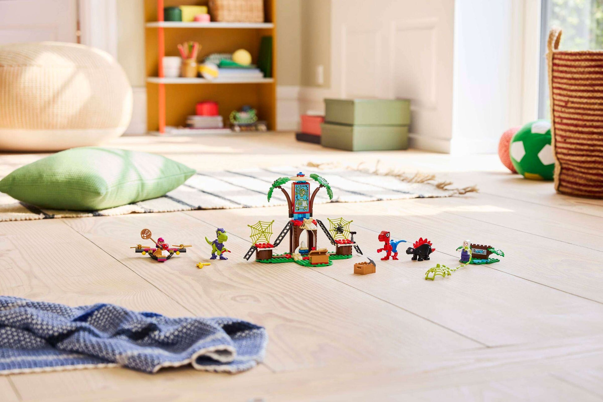 The Legos - Toyhouse LEGO® Marvel Spidey and Gobby's Raptor Battle at Tree House HQ playset is displayed on a wooden floor in a bright, tidy playroom with cushions and a green soccer ball in the background.