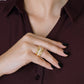 A person in a burgundy shirt shows their black-painted nails and three stacked gold rings, including the Anabel Aram Cheval Chain Stack Ring.