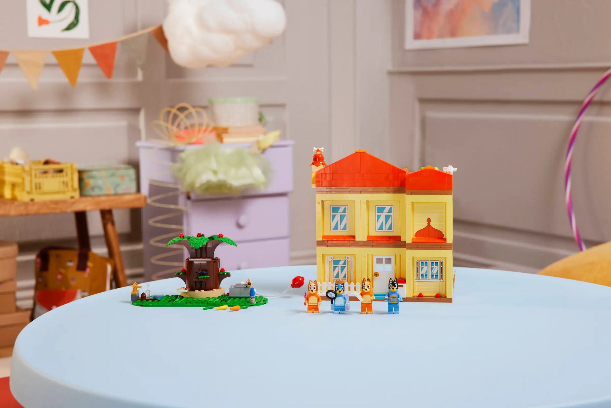 The LEGO® Bluey's Family House set by Legos - Toyhouse is displayed on a light blue round table in a colorful, decorated room.