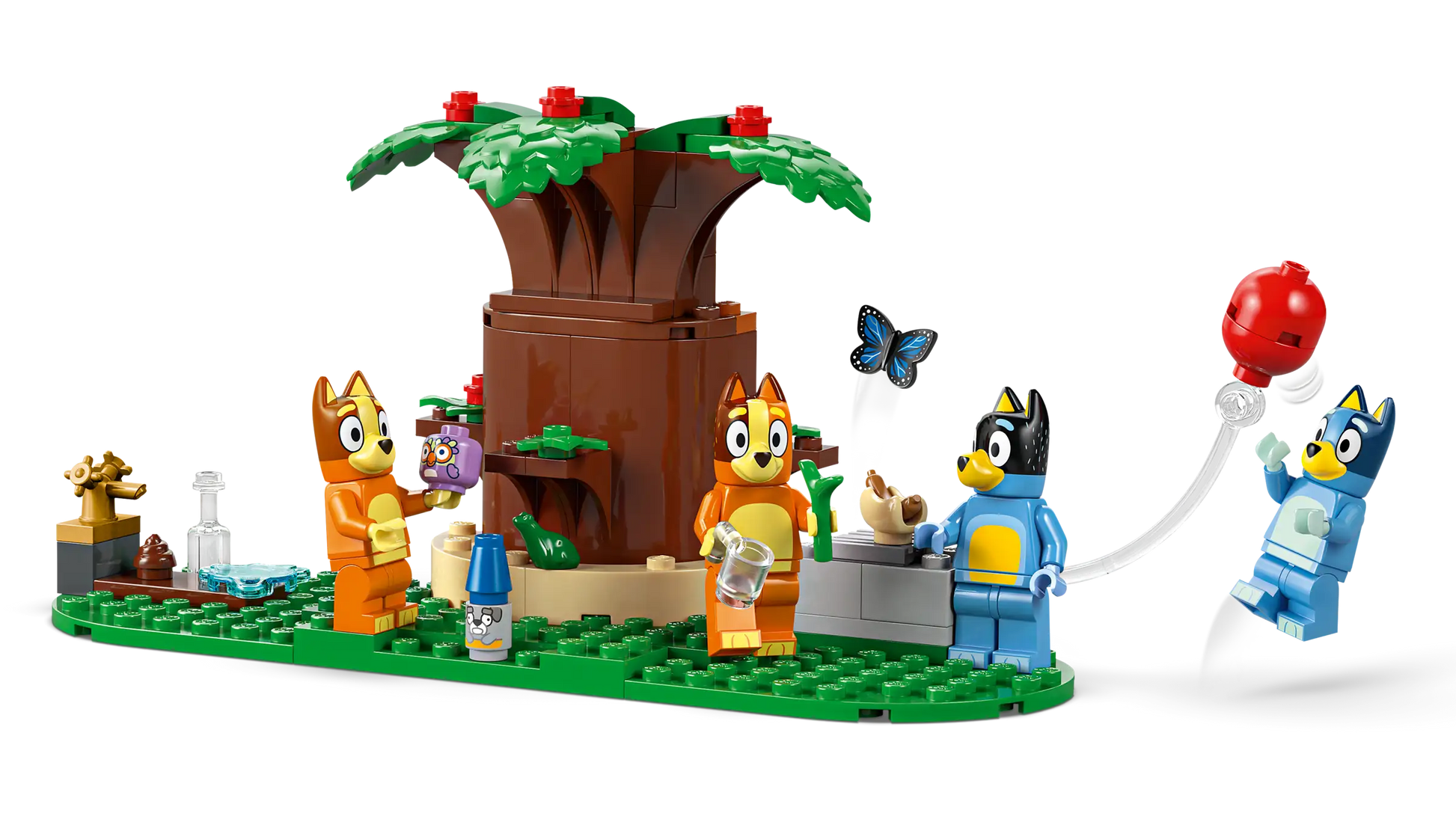 Four cartoon dog LEGO figures play at Bluey's Family House, featuring a tree, butterfly, balloon, water bottles, and fun accessories on a green base—perfect for fans of Legos - Toyhouse and the LEGO® Bluey's Family House set.