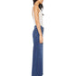 A woman stands in profile against a white background, wearing Mother’s The Undercover high rise wide leg jeans in recycled stretch denim, paired with a white sleeveless top and heeled sandals.
