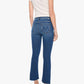 A woman stands with her back to the camera, wearing a short-sleeve beige shirt and Mother’s The Insider Ankle Step Fray blue cropped ankle jeans crafted from stretch denim, paired with silver high-heeled shoes.