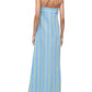 A person is shown from the back wearing the Staud Laura Linen Dress, a sleeveless blue and green striped dress with adjustable spaghetti straps, paired with flip-flops.
