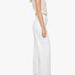 A woman stands in profile against a plain white background, wearing The Lemon Twist Skimp high-rise wide leg pants by Mother, styled with a sheer white t-shirt, black heeled sandals, and bracelets.