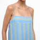A person wearing the Staud Laura Linen Dress, featuring blue and green stripes and adjustable spaghetti straps, is shown from shoulders to mid-torso against a plain background.