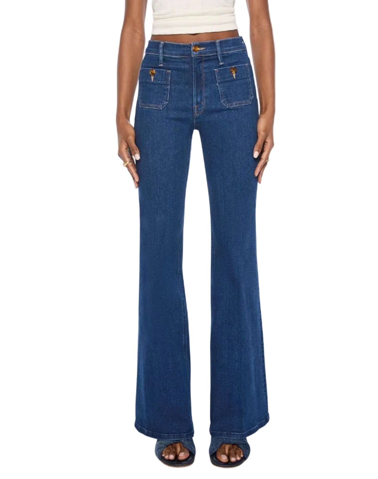 Model wears The Patch Pocket Doozy high-rise flare jeans by Mother, crafted from dark blue stretch denim with front patch pockets, paired with a sleeveless white crop top; shown from waist to feet.