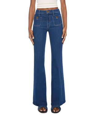 Model wears The Patch Pocket Doozy high-rise flare jeans by Mother, crafted from dark blue stretch denim with front patch pockets, paired with a sleeveless white crop top; shown from waist to feet.