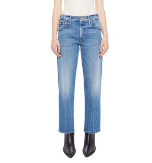 A person wearing Mother’s The Newbie Ankle mid-rise straight-leg blue jeans in rigid denim, a white top, and black pointed-toe boots, stands against a plain white background.