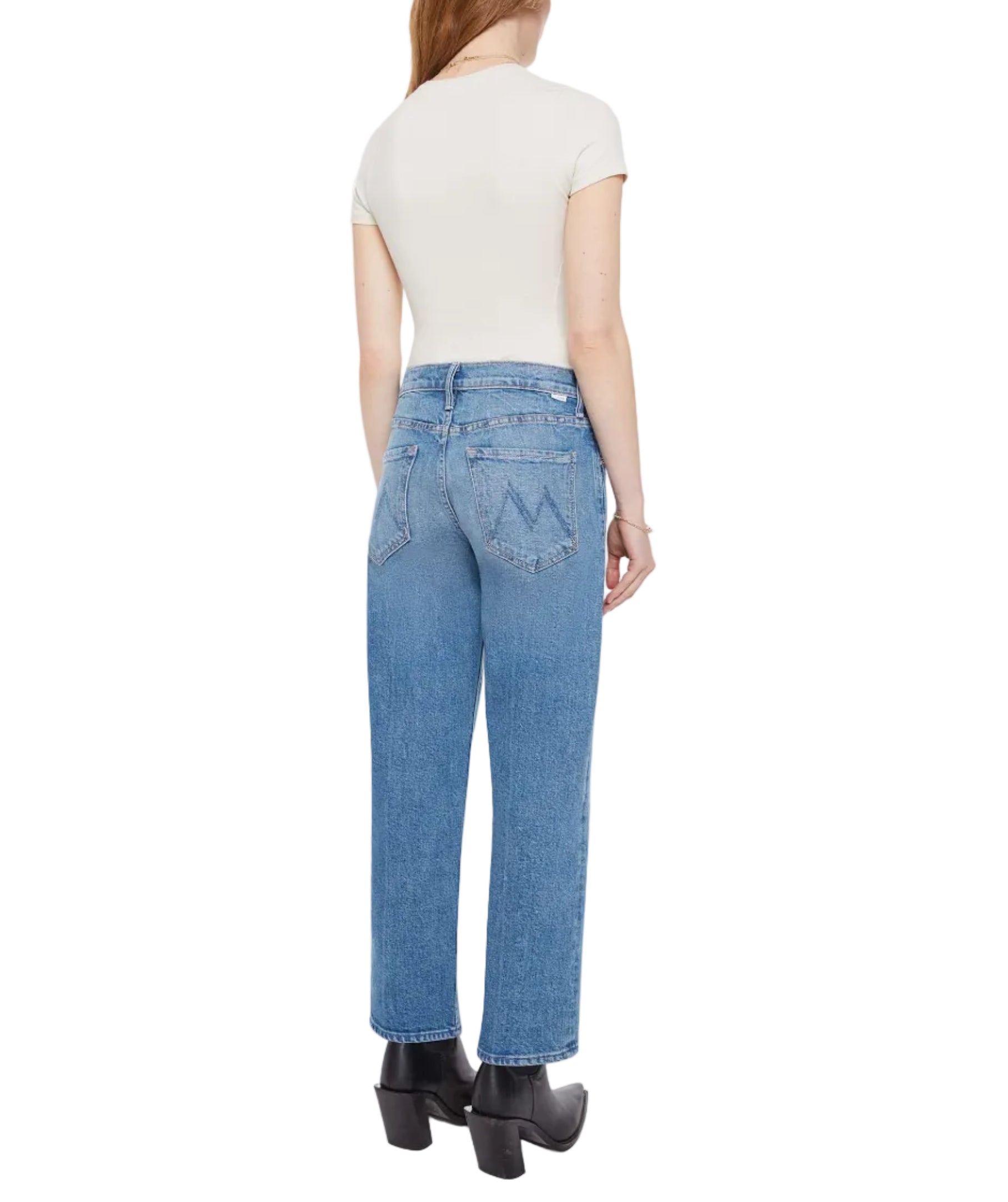 A woman faces away in a white short-sleeve shirt, black heeled boots, and Mother’s The Newbie Ankle rigid denim jeans, set against a plain white background.