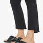 A person wearing black slide sandals and Mother’s The Insider Crop Step Fray jeans, photographed from the knees down against a white background.