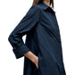 A woman wearing the TWP Hankerchief Midi Jenny's Gown, a long-sleeve dark blue cotton collared shirt dress with her hand in the pocket, shown from shoulders to mid-thigh.