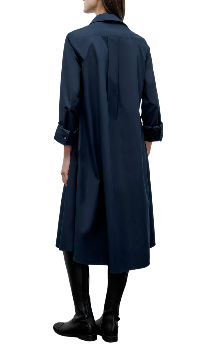 Person shown from the back wearing TWP's Hankerchief Midi Jenny's Gown—a long-sleeve, dark blue cotton shirt dress with rolled cuffs—paired with black knee-high boots.