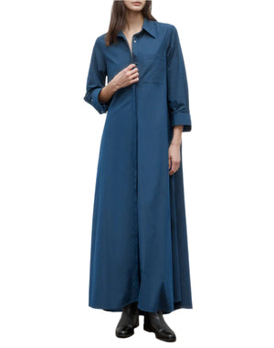 A person wearing the Jenny's Cotton Gown by TWP, an oversized maxi shirt dress made from Italian cotton shirting, pairs it with black ankle boots while standing against a plain white background.