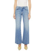 Model wearing "The Bookie Twist Skimp" high-waisted, wide-leg jeans in light blue by Mother, styled with beige pointed shoes; photographed from waist to feet against a white background.