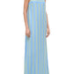 A person in the Staud Laura Linen Dress—a sleeveless, blue and green striped dress with adjustable spaghetti straps—paired with flip-flops, stands against a white background.