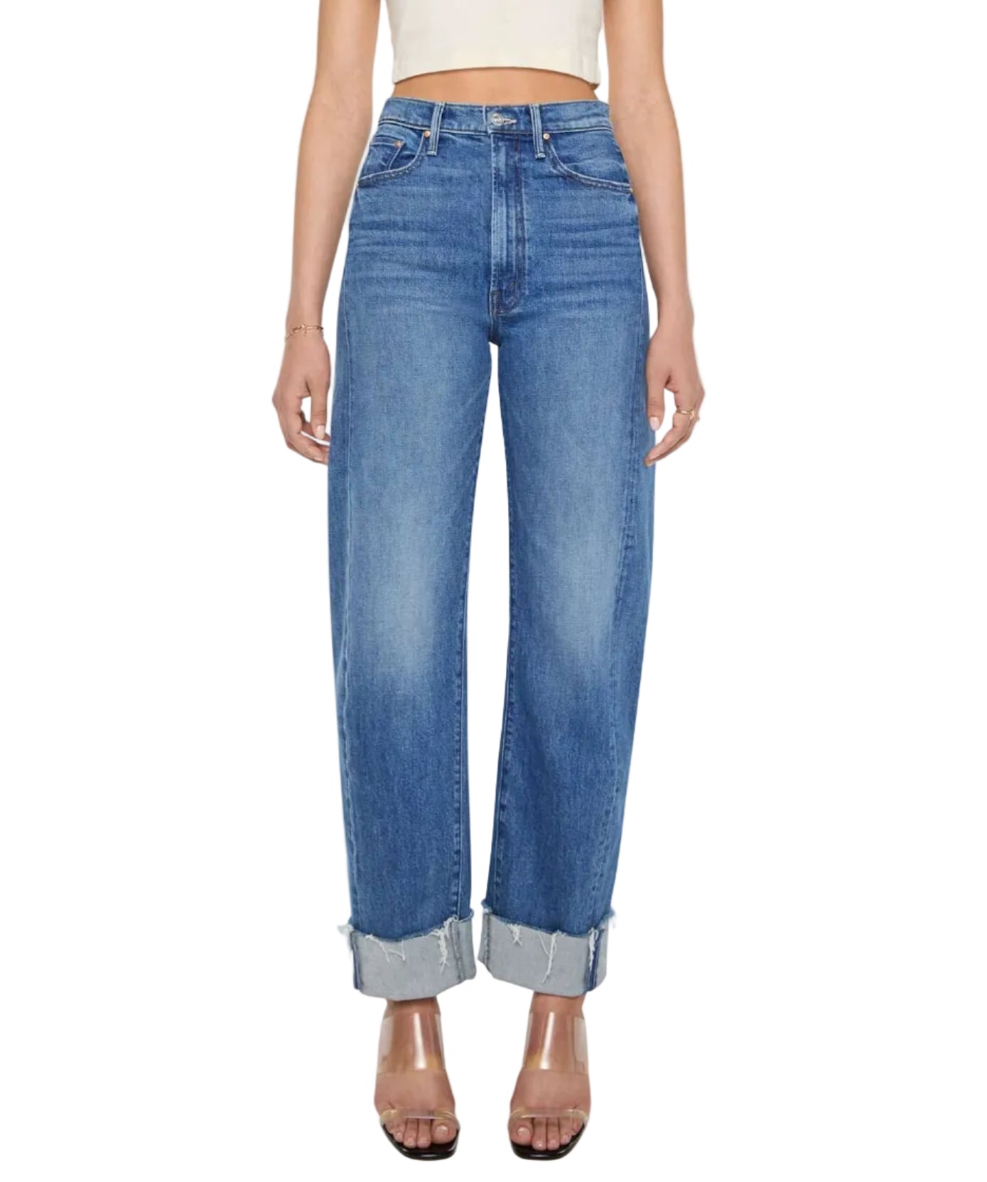 Wearing Mother’s Half Pipe Flood Cuff Fray high-waisted, wide leg jeans crafted from SUPERIOR denim with large cuffs and pairing them with a white crop top, the look is finished with clear heeled sandals.
