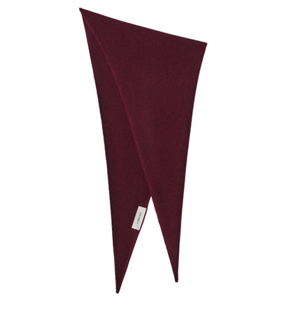 The Florianne Scarf by Lisa Yang is a dark red, asymmetrical wool accessory featuring pointed ends and a white label, effortlessly doubling as a chic headscarf for versatile styling.