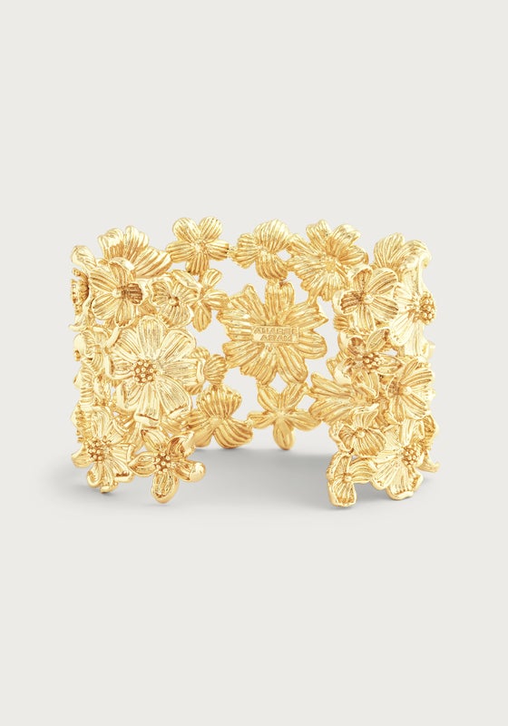 The Anabel Aram Wildflowers Gold Wide Cuff features an intricate raised floral design and a radiant 18k gold plated finish, making it a standout statement piece.