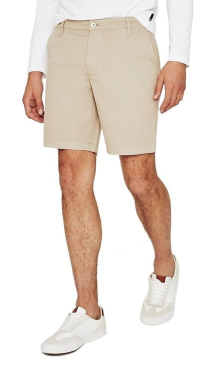 Man wearing slim fit AG Jeans Wanderer Short beige shorts and white sneakers.