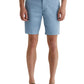 A person wearing light blue AG Jeans Wanderer Shorts, a white shirt, and brown loafers showcases a tailored look against a plain white background.
