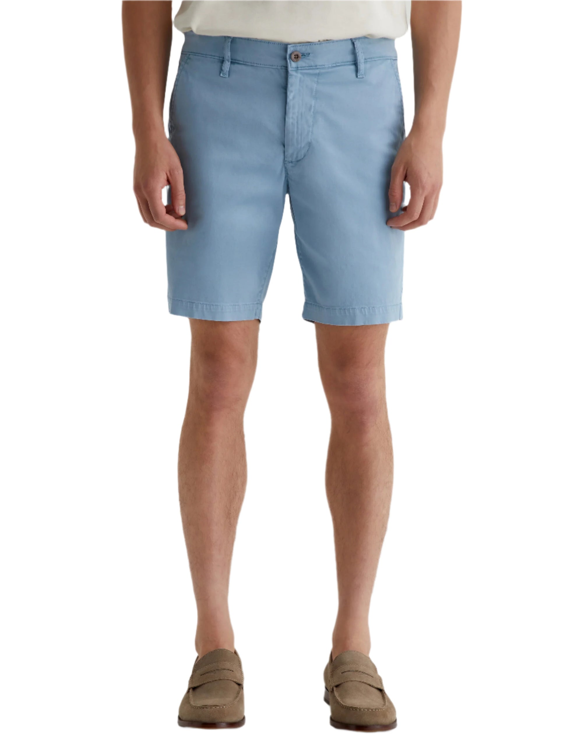 A person wearing light blue AG Jeans Wanderer Shorts, a white shirt, and brown loafers showcases a tailored look against a plain white background.