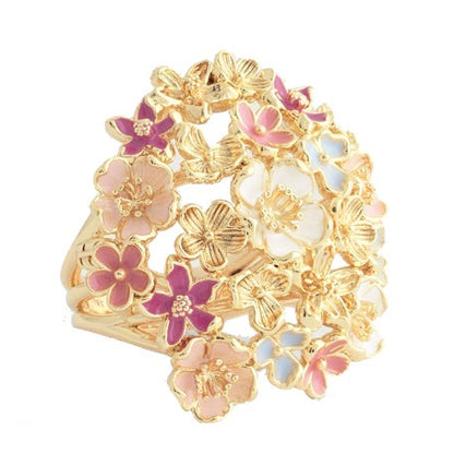 The Wildflowers Gathered Ring by Anabel Aram is an 18k gold-dipped brass ring with delicate floral designs featuring hand-painted enamel flowers in pink, white, and light blue.