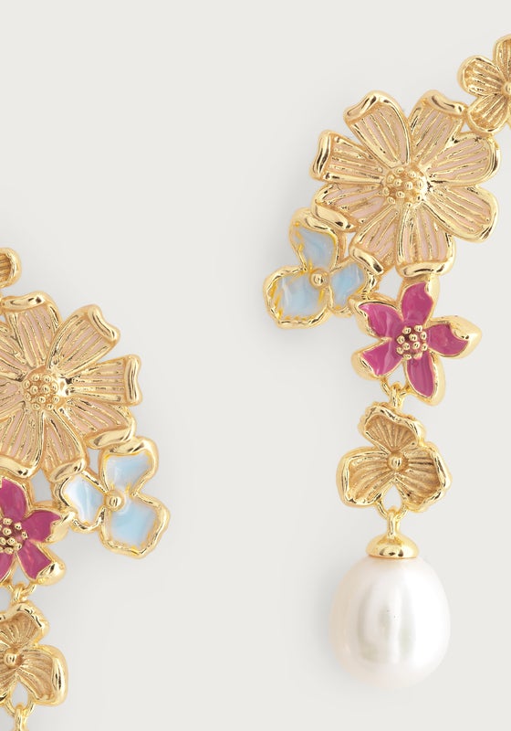 Close-up of Anabel Aram’s Wildflowers Pearl Drop Earrings: 18k gold-dipped, with pink and blue enamel flowers and a single dangling white pearl.