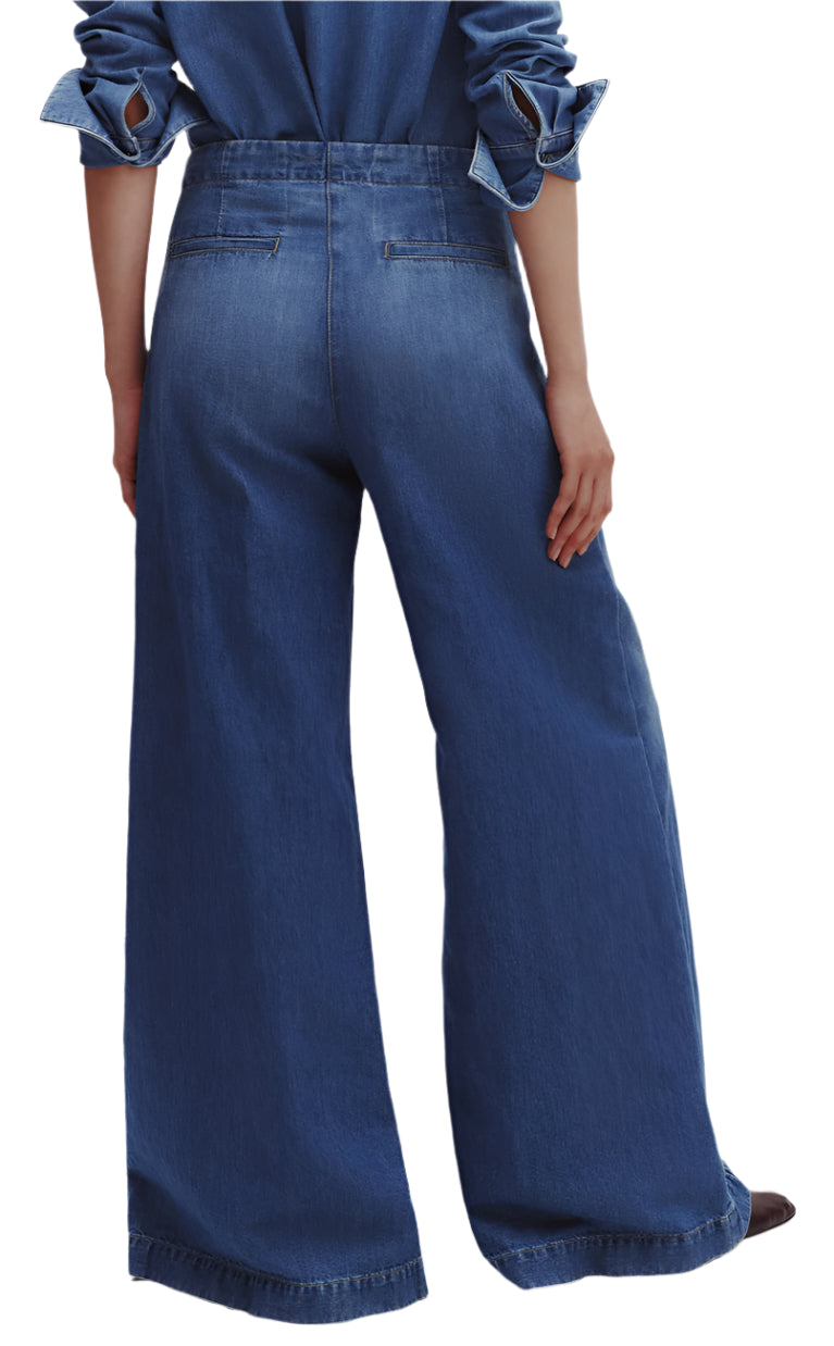 A person is seen from the back wearing the TWP Dancing In The Dark Jeans, which are relaxed fit, wide-leg blue denim pants, paired with a matching denim shirt.
