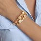 A person in a light blue shirt wears the Anabel Aram Wildflowers Bangle, a hand-painted enamel bracelet featuring gold floral details with white and red accents on their wrist.