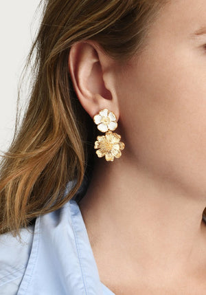 Close-up of a woman's ear wearing Anabel Aram’s Wildflowers Mixed Drop Earrings—double flower-shaped gold drops featuring a small white stud and a larger gold bloom.