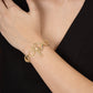A person in a sleeveless black outfit showcases the Anabel Aram Cheval Chain Bracelet, featuring gold plating and a bar and ring toggle clasp, on their wrist.