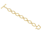 The Anabel Aram Cheval Chain Bracelet features gold-plated oval links with textured detailing, a T-bar clasp, and a D-shaped toggle closure, shown against a white background.