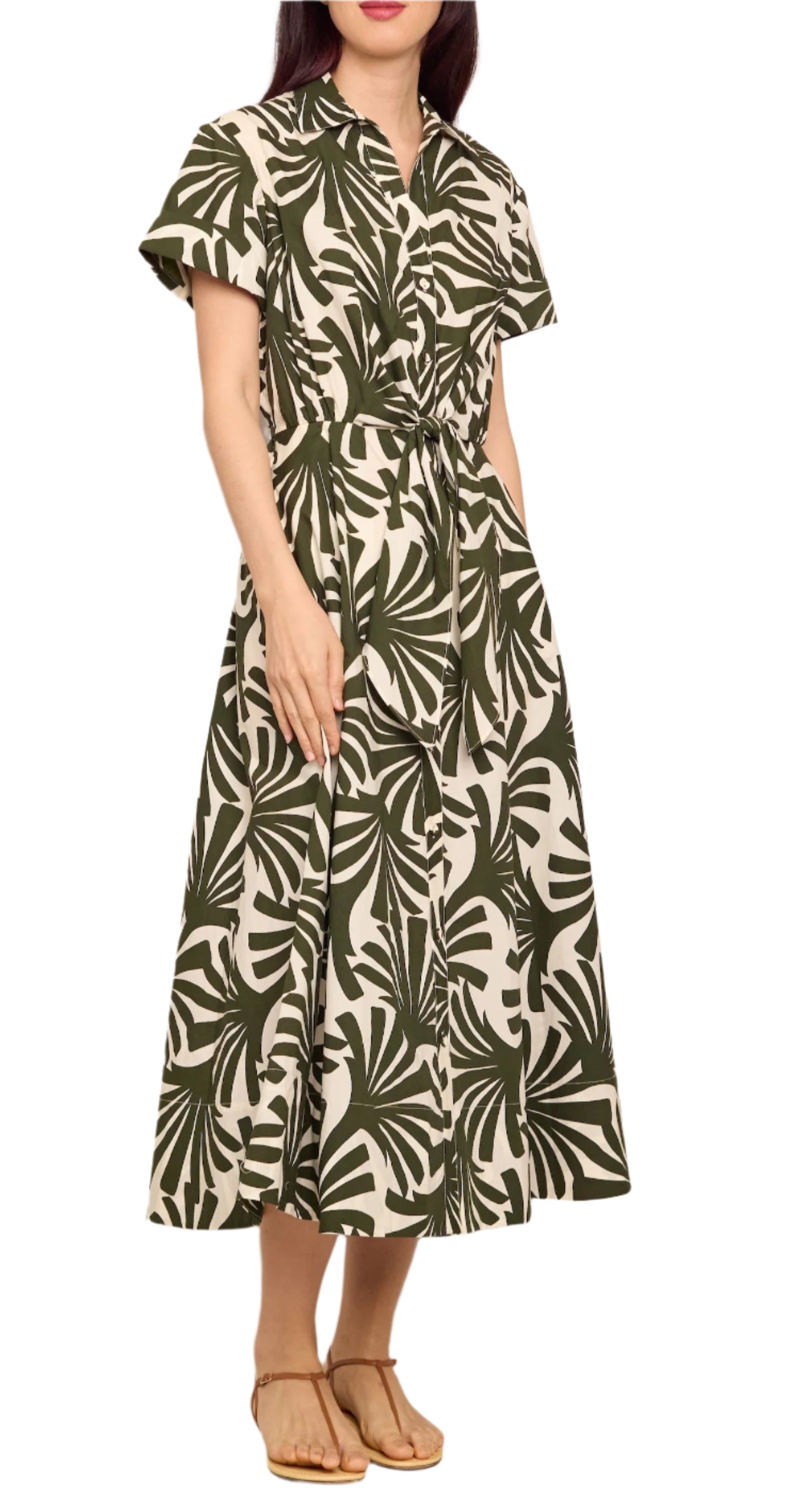 Woman wearing the Cara Cara Asbury Midi Dress, a short-sleeve, button-down, ankle-length dress with a green and white tropical leaf print and self-tie waist, paired with tan sandals.