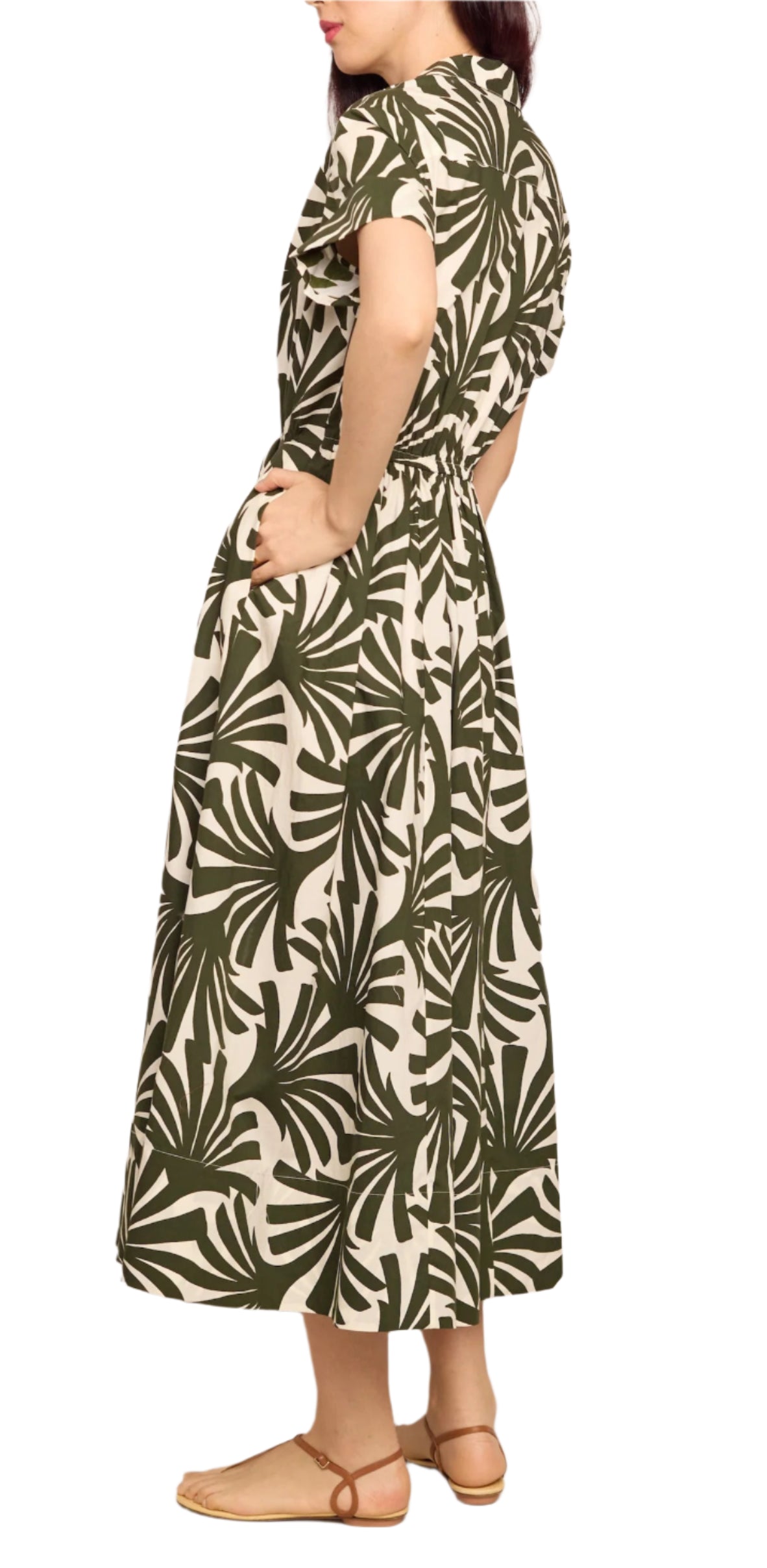 Woman wearing the Cara Cara Asbury Midi Dress in a green and white leaf pattern with short sleeves and self-tie waist, paired with tan sandals, standing in profile against a white background.