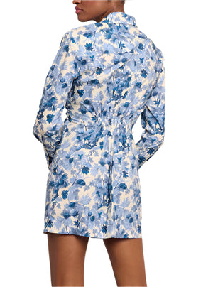 A person is seen from the back wearing the Juni Shirt Dress by Cara Cara, featuring a floral-print with cuffed long sleeves and blue and white flower patterns.