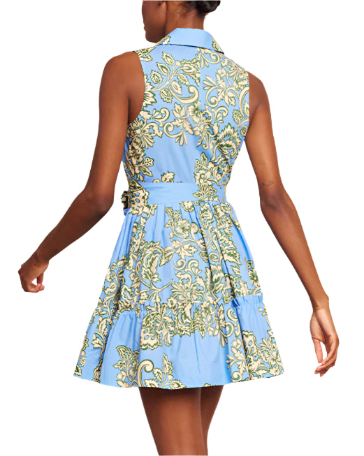 A woman is wearing the Cara Cara Hannah Mini Dress, a sleeveless blue floral mini with a flared skirt and side seam pockets, shown from the back.