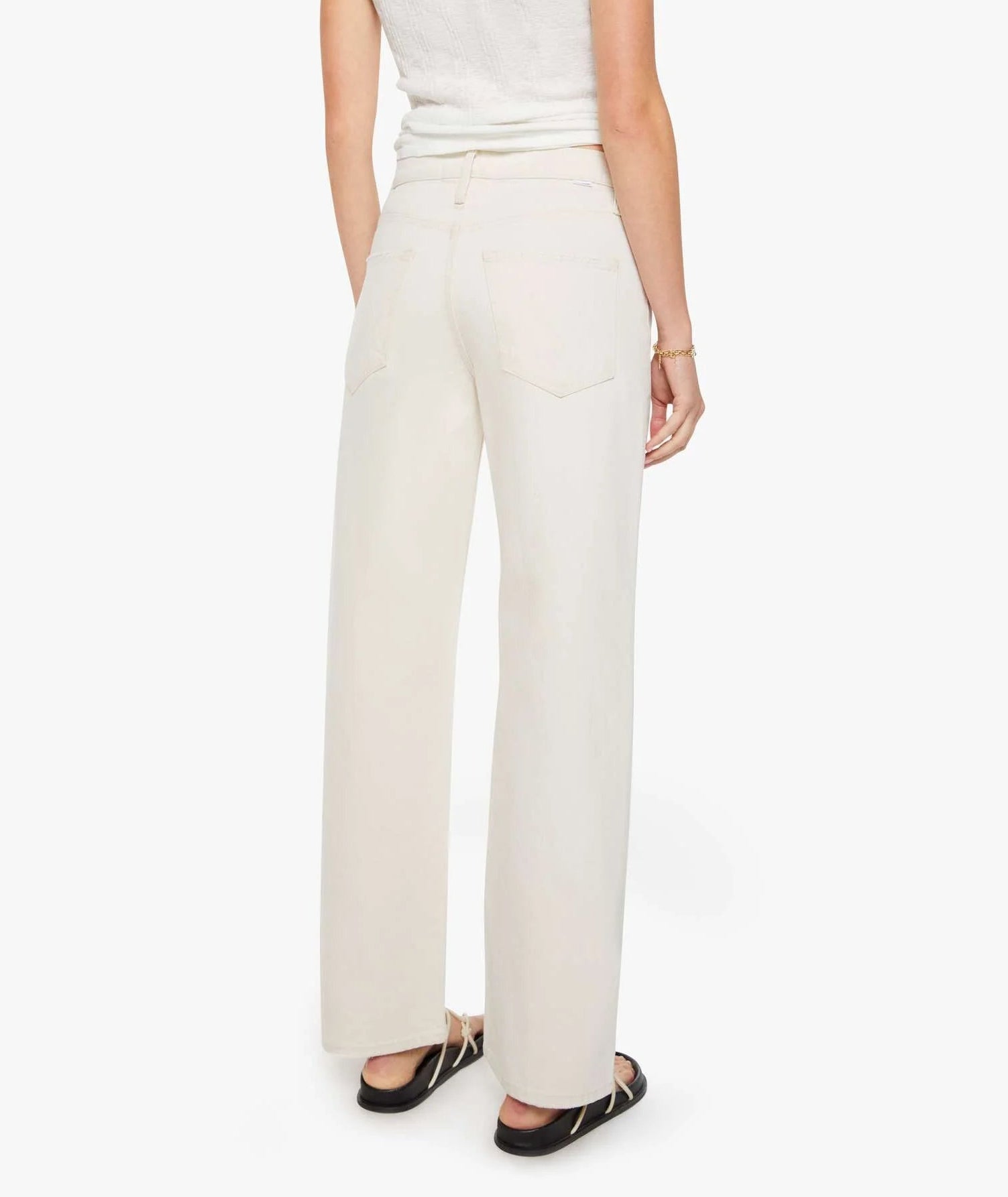A person stands facing away wearing the Dodger Skimp high-waisted, loose straight leg pants in SUPERIOR cotton by Mother and a sleeveless top.