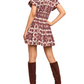 A person stands with their back to the camera, wearing the Cara Cara Nash Mini Dress with a charming pattern and knee-high brown suede boots for a perfect fit.