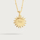 The Milos Soleil Charm by Anabel Aram is a gold sunburst necklace with a sun-shaped pendant engraved with "NASEL ARAM," inspired by Mediterranean sun jewelry, shown against a plain light background.