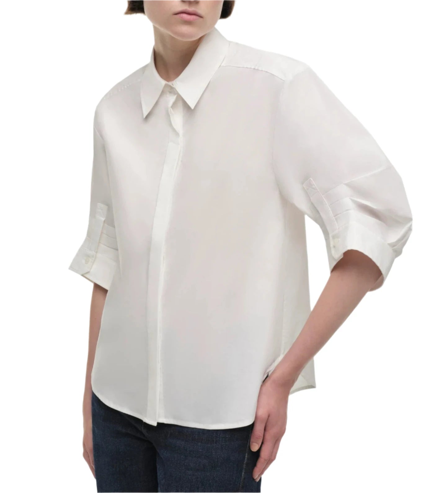 Person wearing a white Simkhai Gemma Shirt, which has a tailored fit and classic collar, paired with dark jeans against a plain background.