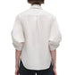 A person wearing the Simkhai Gemma Shirt, a tailored-fit blouse, with rolled-up cuffs and black pants, viewed from the back.