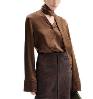Model wearing CO's Scarf Blouse in brown silk with a tie collar and long wide cuffs, paired with a dark brown skirt, set against a white background.
